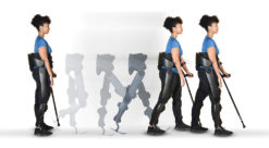 A woman walks assisted with an exoskeleton around her back and legs