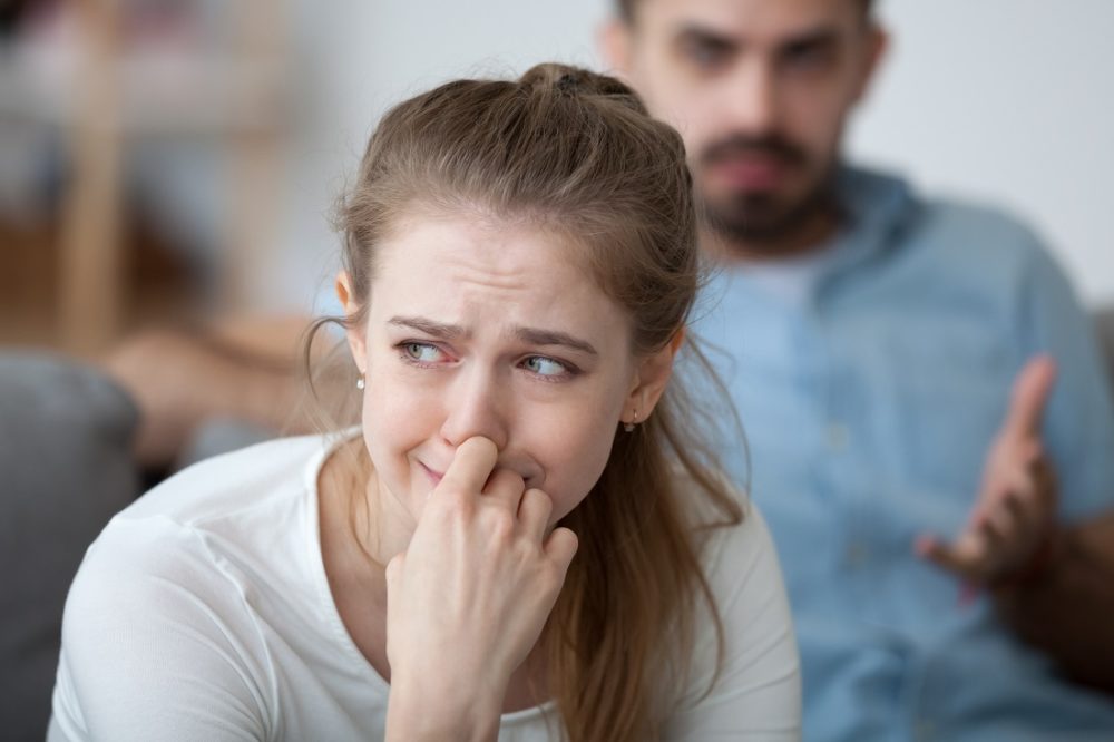 A woman on the verge of tears looks away as a man tries to talk to her.