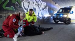 Ambulance personel treat an unconscious person on the street