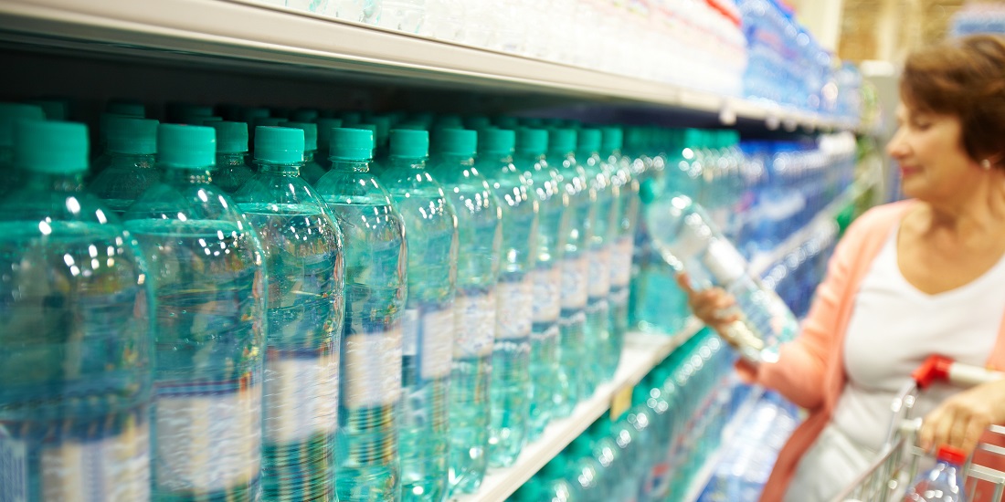 A woman taking a plastic bottle of something from a shelf in a store
