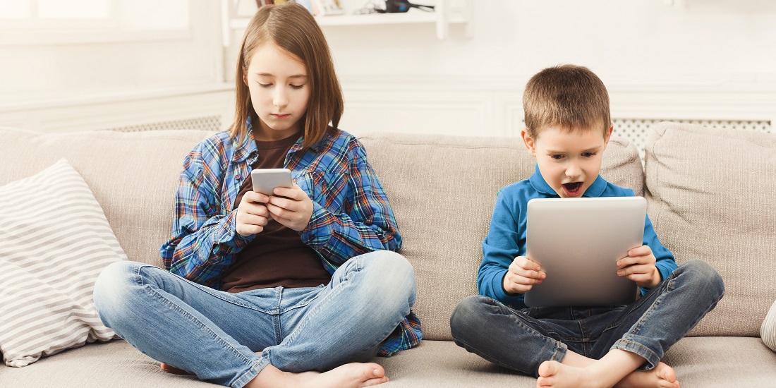 Two children playing video games on a couch