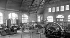 Interior from the old thermal power laboratory at the Norwegian University of Technology. The picture shows machines and equipment and people at work.
