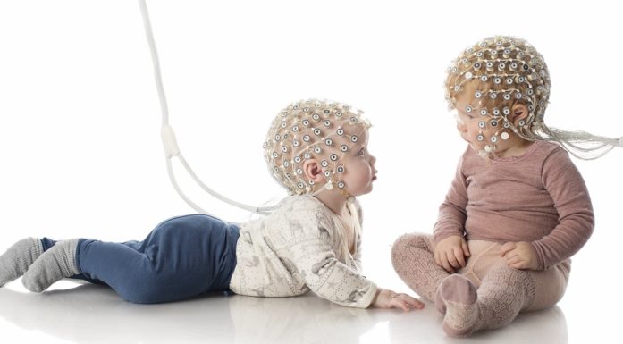 Two toddlers with some kind of electrical equipment on their heads