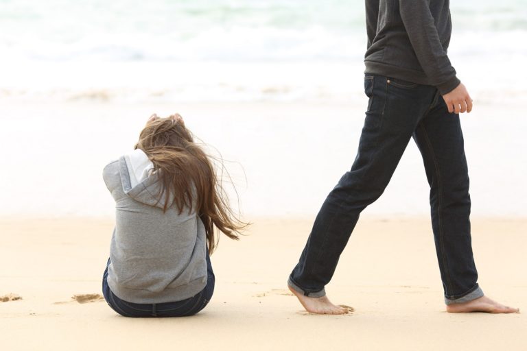 A man leaving an upset woman on a beach