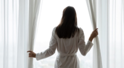 A woman opening curtains at a hotel