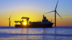 Offshore wind turbines and ship in silhouette in front of beautiful sunset.