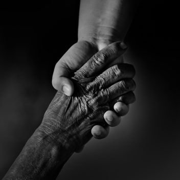 Close-up of a young person and an oldperson holding hands.