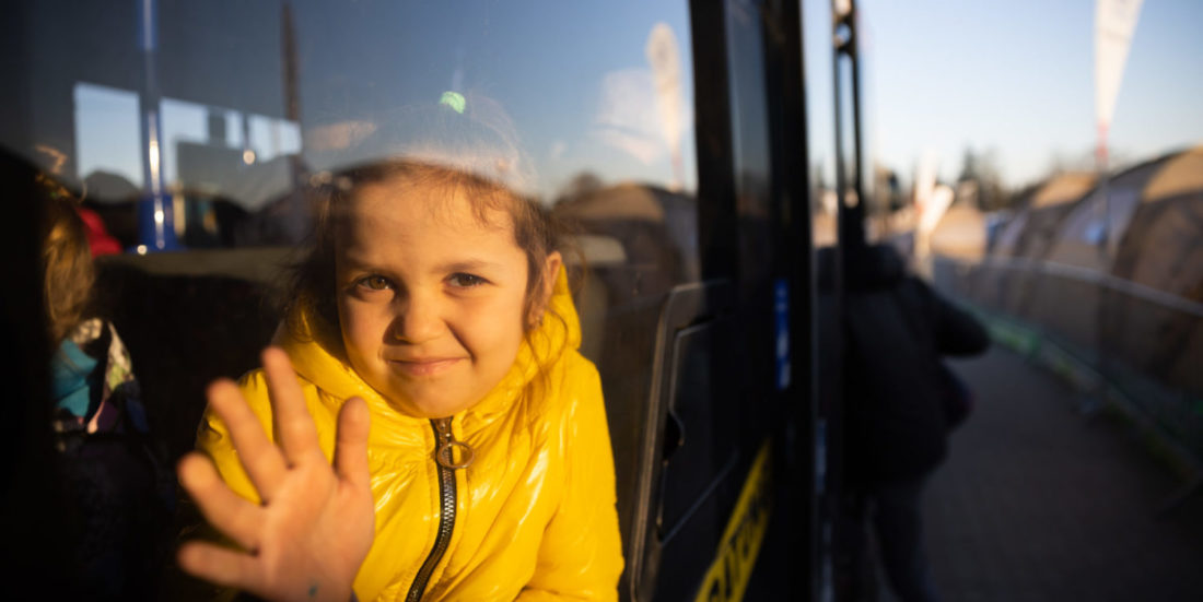 Young girl fleeing Ukraine, waving Liten jente som har flyktet fra Ukraina , waving out a bus window.
