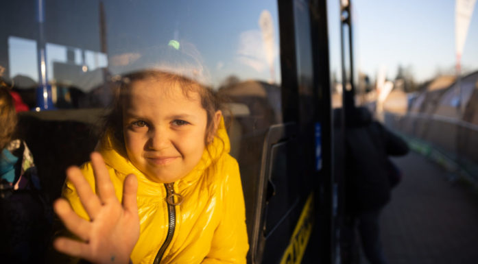 Young girl fleeing Ukraine, waving Liten jente som har flyktet fra Ukraina , waving out a bus window.