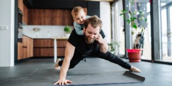 Man exercising with child on back.