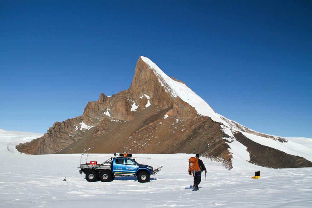 Six-wheeler pickup truck below a nunatak in Antarctica