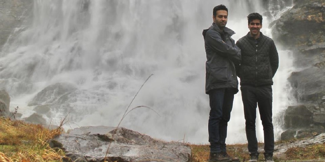 Two men in front of a waterfall