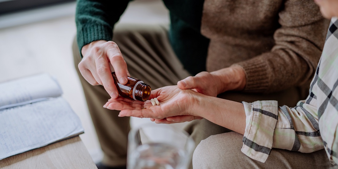 Home-based hospital care. Picture of a man giving pills to a woman