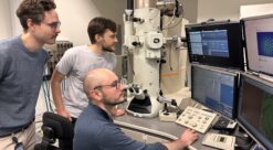 Three researchers looking at computer screens of STEM microscopy