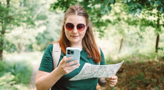 Woman in woods with map and phone finding her way