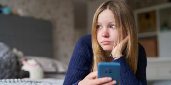 Young girl looking up from mobile phone. Photo.