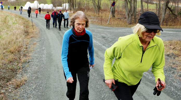 Two elderly women runners ahead of a group of walkers on dirt path. Photo.
