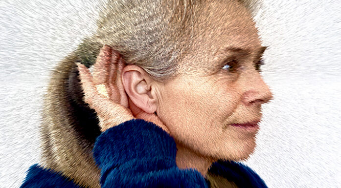 Woman with her hand cupping her ear to improve hearing. Photo illustration.