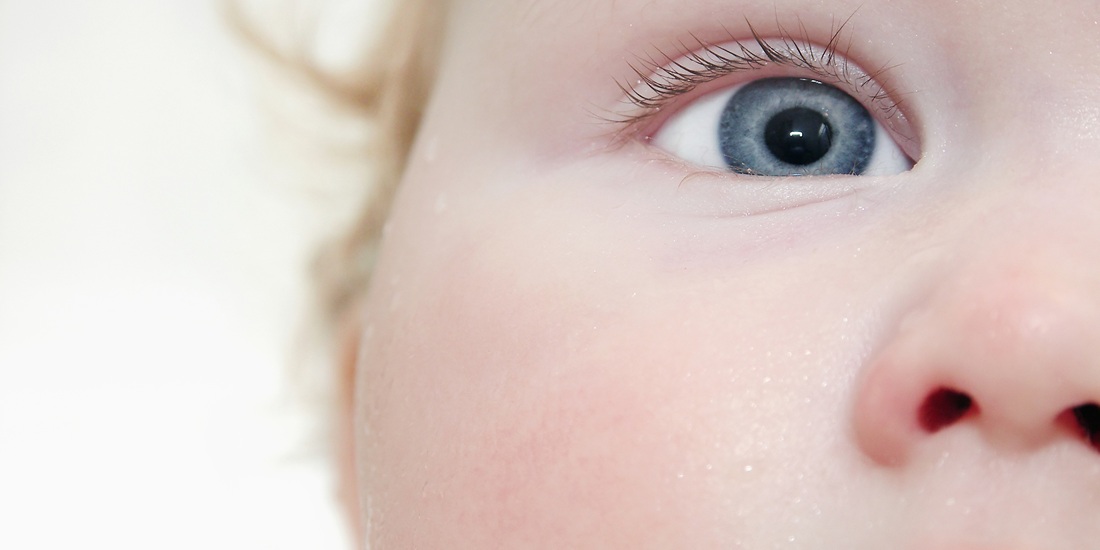 Closeup of an infant's face and one blue eye. Photo illustration.