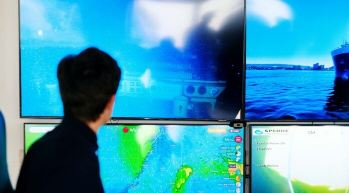 Man sitting in front of big computer screens with ocean images. Photo.