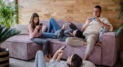 A family with two little daughters, everyone is using mobile phone in the living room.