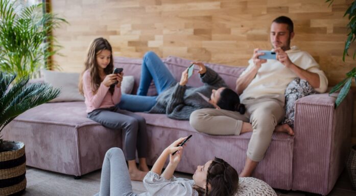 A family with two little daughters, everyone is using mobile phone in the living room.