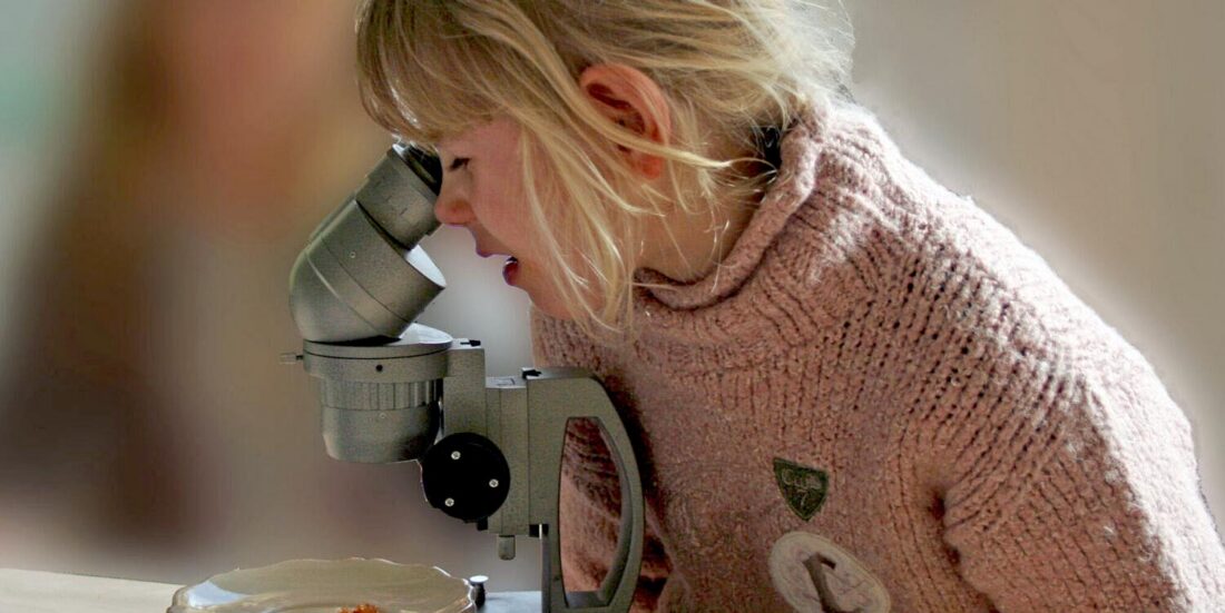 Young girl looking into a microscope. Photo illustration.