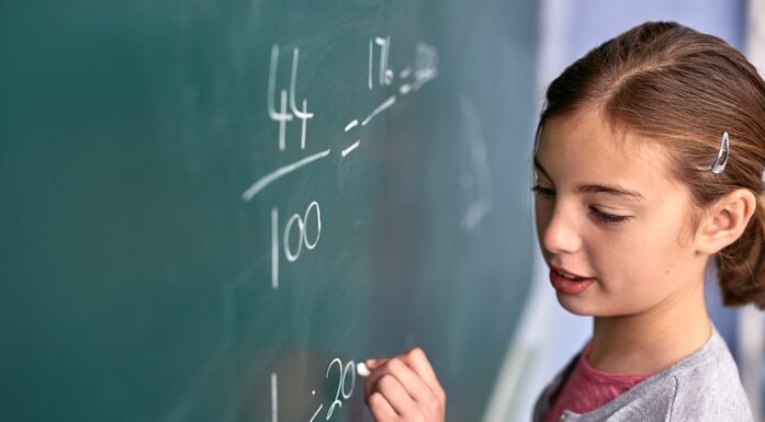 Young girl writing math equations on chalkboard. Illustration photo.