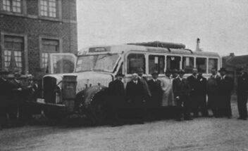 a low resolution black and white photo of men stood in front of a bus