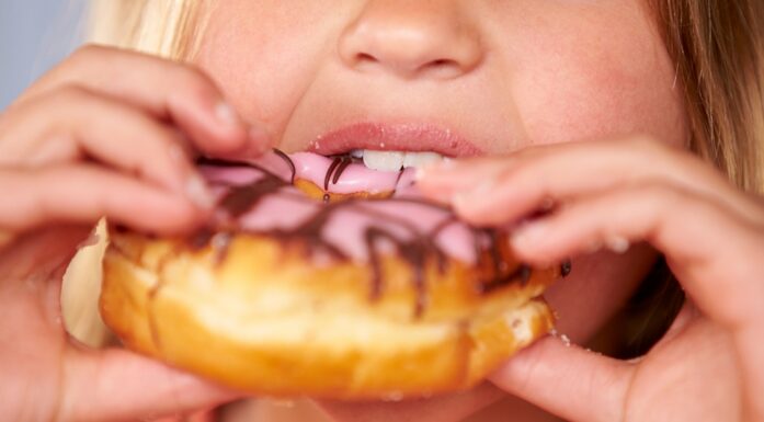 Close Up Of Girl Eating Iced Donut