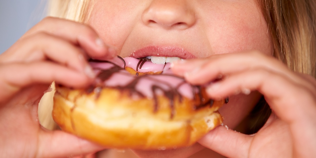 Close Up Of Girl Eating Iced Donut